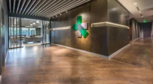 Modern commercial office lobby with wooden luxury vinyl flooring and metal signage wall.